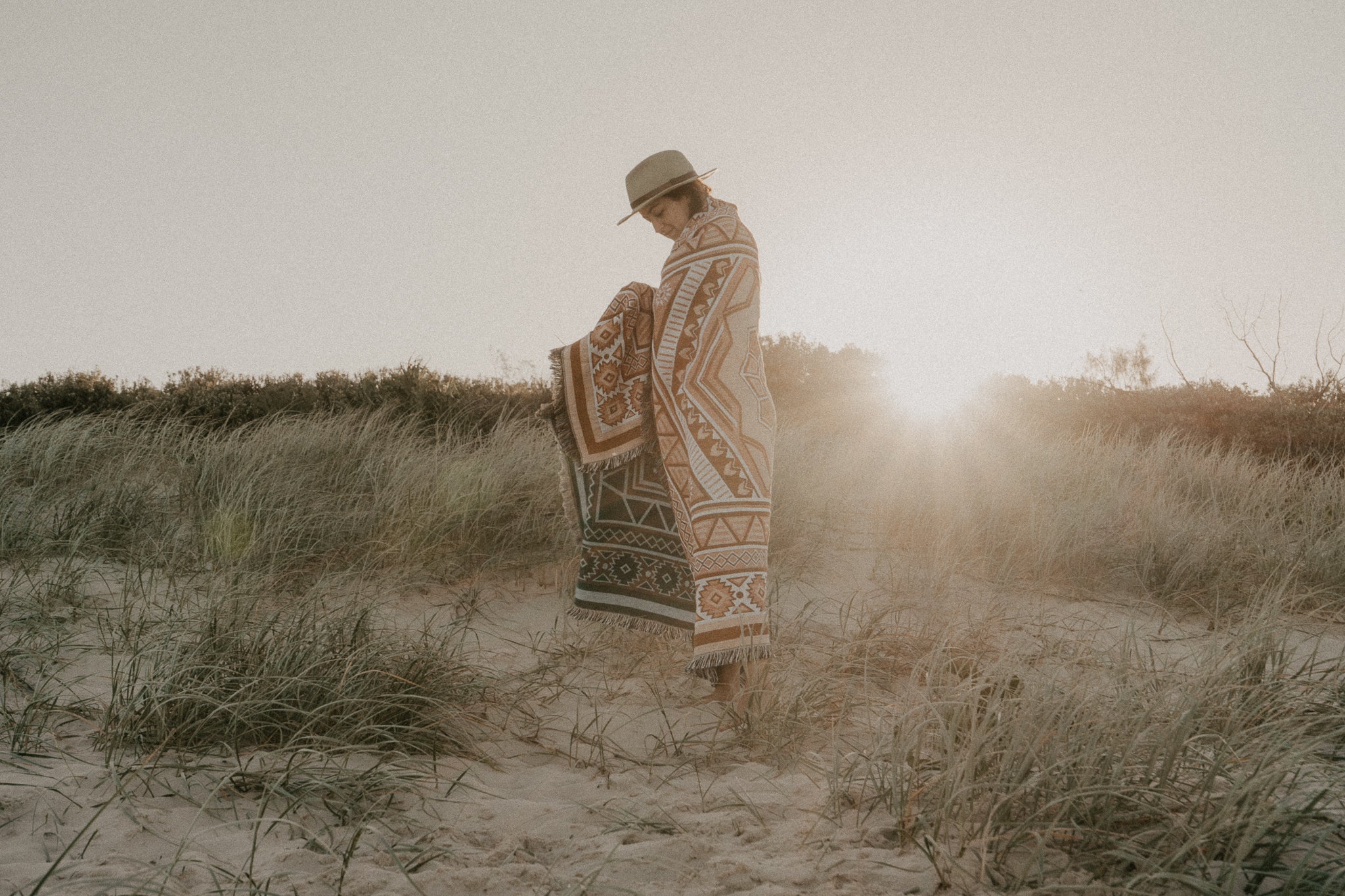 Girl standing in sand Dunes with throw rug wrapped around her