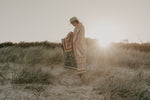 Load image into Gallery viewer, Girl standing in sand Dunes with throw rug wrapped around her
