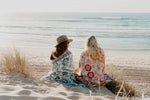 Load image into Gallery viewer, Two girls watching sunrise on beach with pink and green floral florence throw wrapped around them
