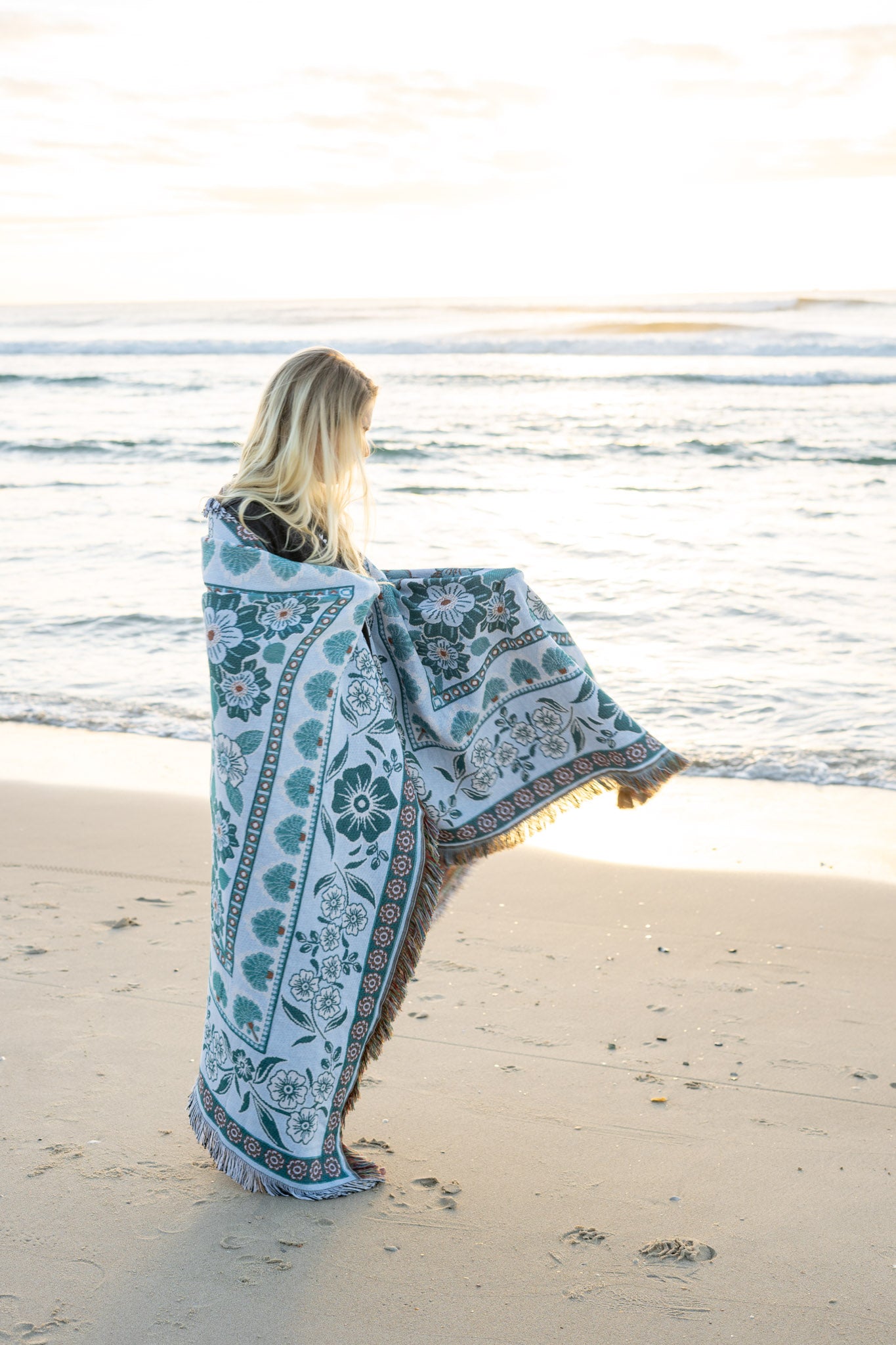Girl on beach with green floral florence throw wrapped around her