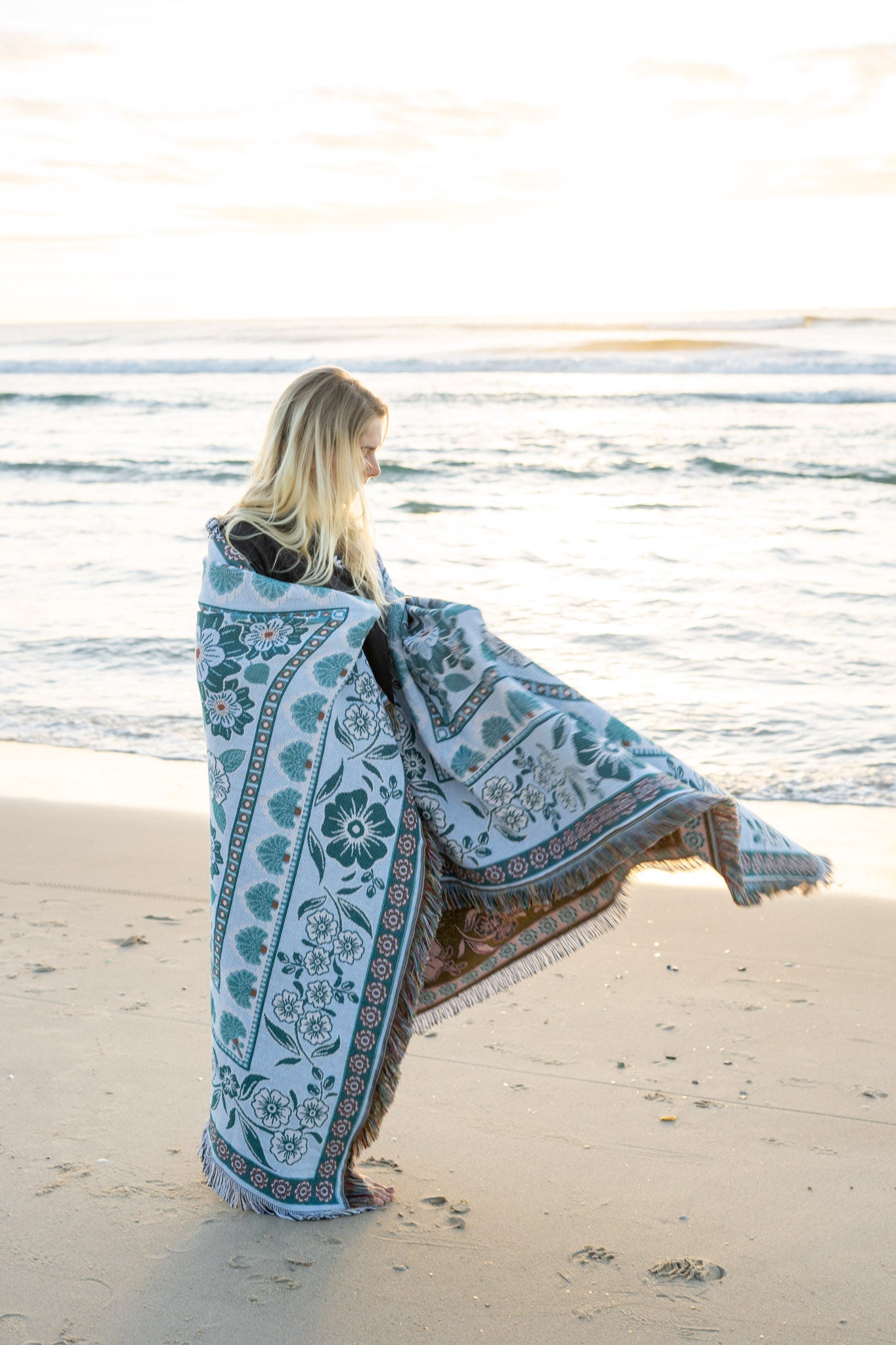 Girl on beach with green floral florence throw wrapped around her