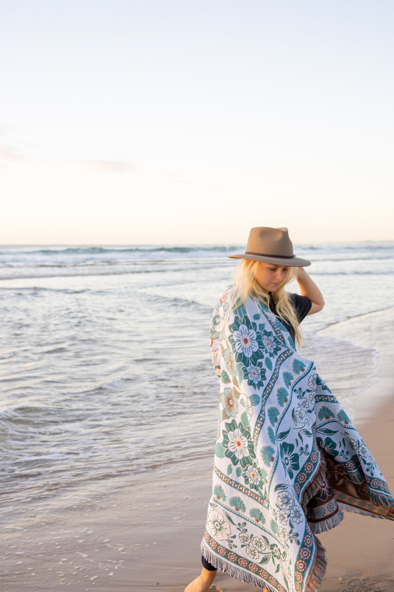 Girl on beach with green floral florence throw wrapped around her