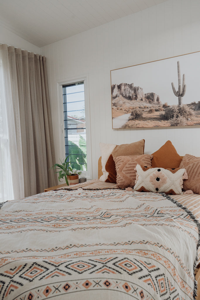 Cotton throw on bed, cactus picture on wall