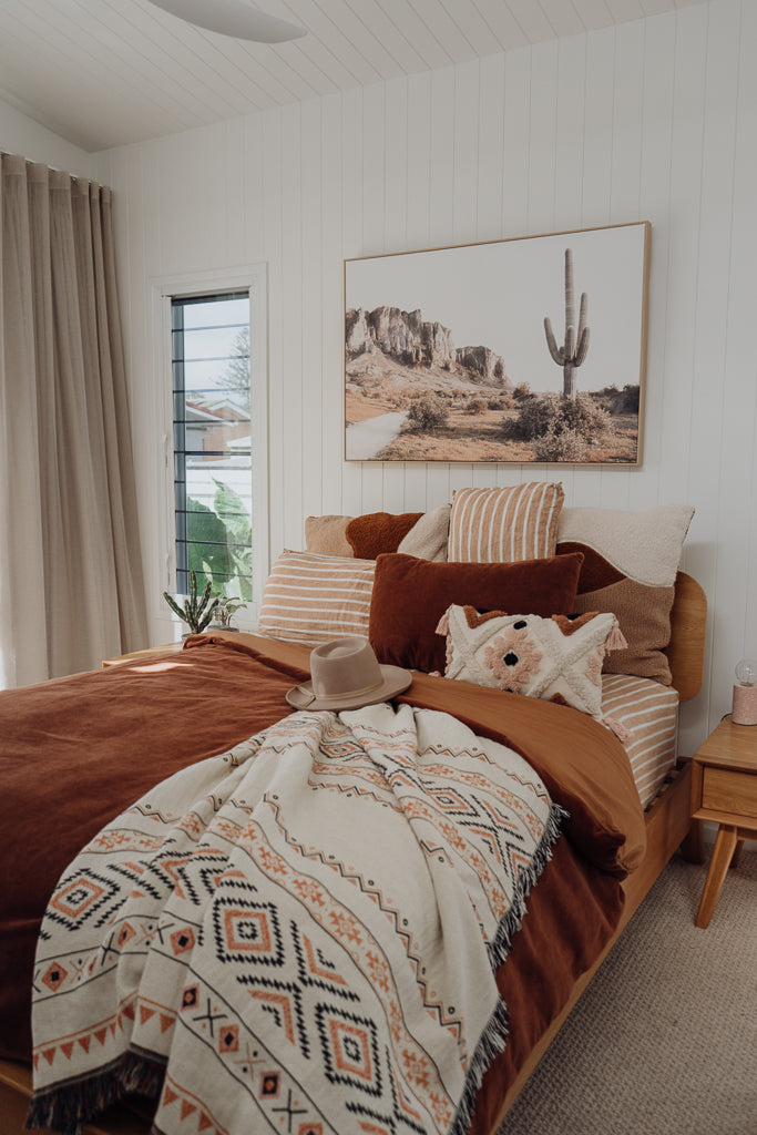 Cotton throw on bed, hat on bed, cactus picture on wall