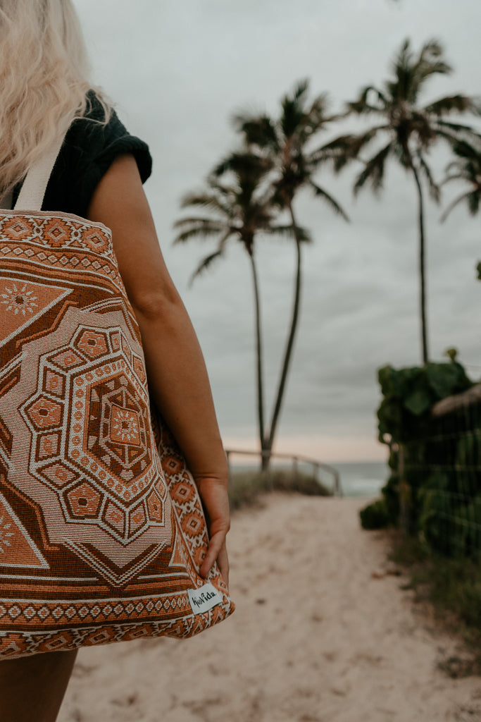 Cropped image of bag on cotton shoulder, palm trees in background