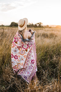 Girl in grass field with pink floral florence throw wrapped around her