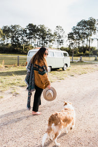 Girl and dog walk towards back of vw kombi with throw rug