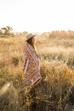 Load image into Gallery viewer, Girl in long grass field with orange sofia throw wrapped around her
