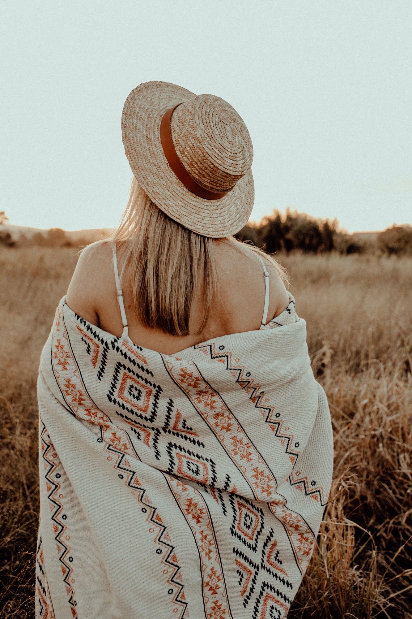 Girl in grass field with white zara throw wrapped around her for warmth